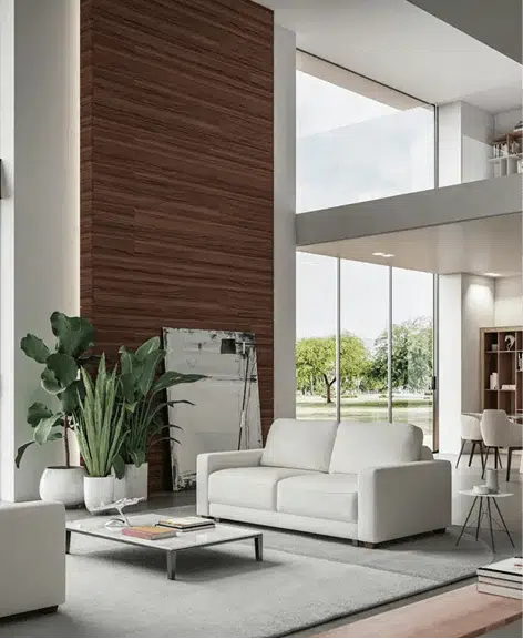 A white leather sofa bed is featured in a spacious modern living room with tall windows, a wood-paneled accent wall, and minimalist furniture. A low metal coffee table and large potted plant complete the sleek, airy design.